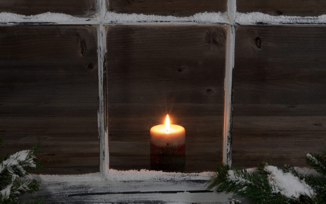 Snowy window and fir branches with glowing candle